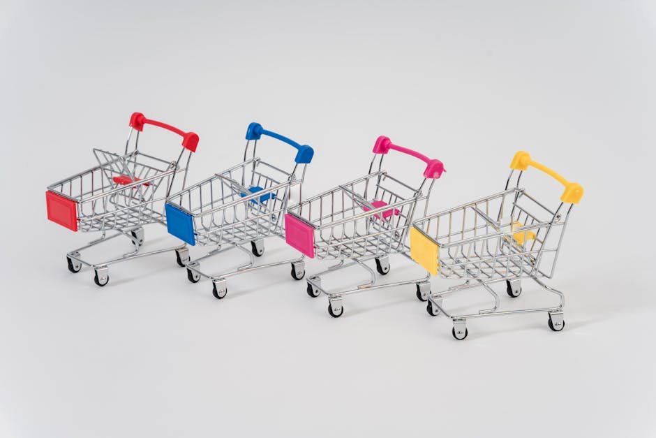 Four miniature shopping carts with colorful handles aligned on a white background for conceptual business imagery.